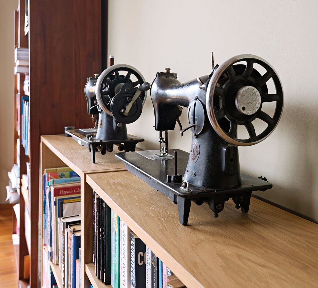 Vintage sewing machines sitting on top of a bookshelf.
