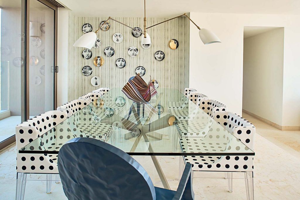 The dining area is furnished with a table by Cattelan Italia adorned with plates by Fornasetti, and surrounded by Kartell chairs.