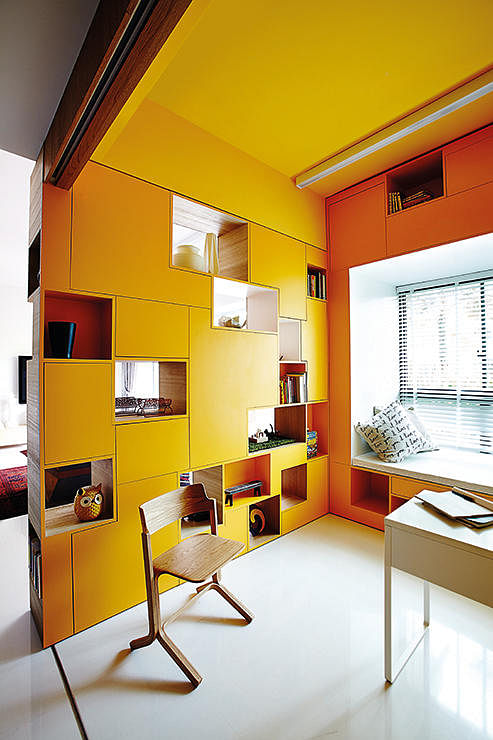 A full-height partition, that houses storage space and display shelving, zones the study area, creating a semi-private working space for the family.