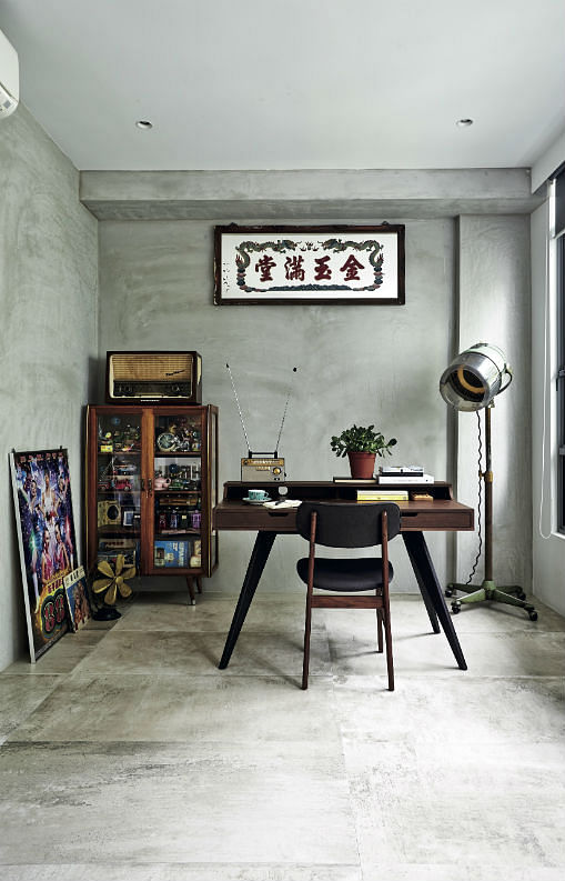 Part of the living area, the open study is situated in the footprint of a former bedroom. A framed mirror Roystan Tan bought in Taiwan hangs above a desk with pencil legs from Commune, while collectibles and colourful toys are stowed in the vintage wooden cabinet behind.