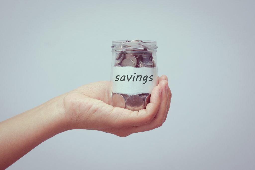 Hand holding a jar of coins with the label "Savings". Home renovation costs can be lowered greatly by approaching or buying direct from factory manufacturers