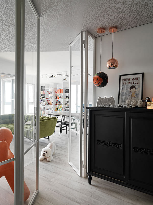Entrance foyer with white framed glass partitions in the simple all-white house with vibrant pops of colour for a Taiwanese toy collector's 2-bedroom apartment