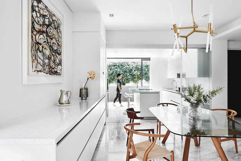A seamless row of white storage cabinets stretching from the kitchen to the dining area