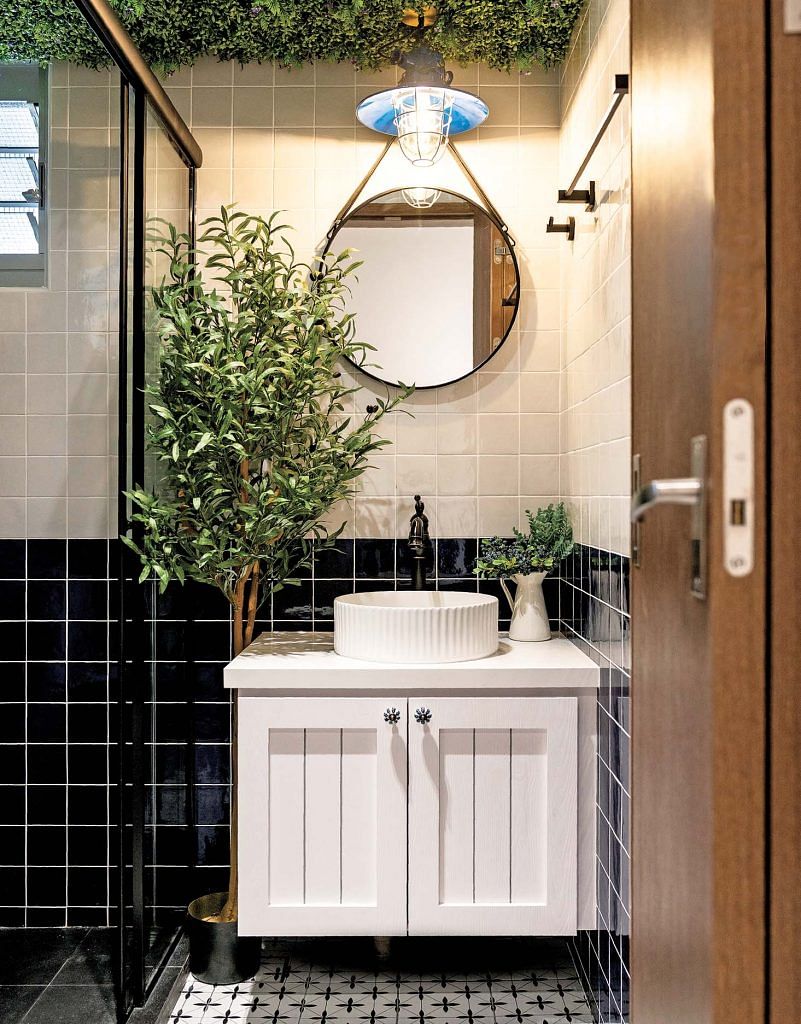 The bathroom features a vanity cabinet in shiplap style. Patterned flooring complements the square blue and off-white wall tiles.