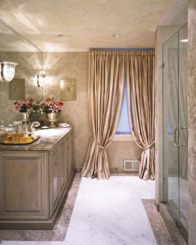 The bathroom vanity is a custom piece with a hand- glazed finish. Drapes and beaded crystal sconces from Sherle Wagner enhance the dramatic effect.
