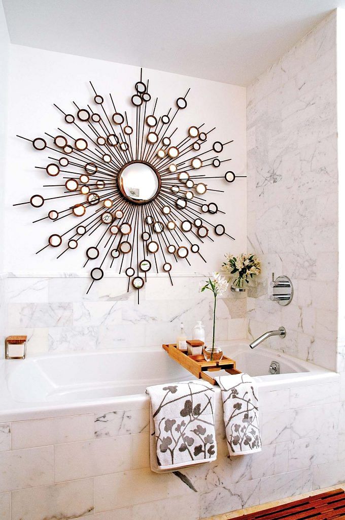An intricate round mirror above a bathtub