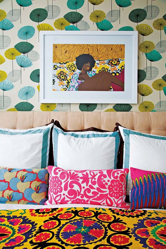 A painting above a colourful bed