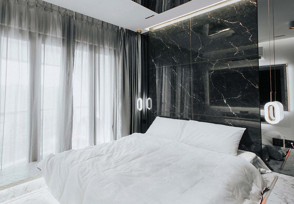 A double bed against a black marble wall