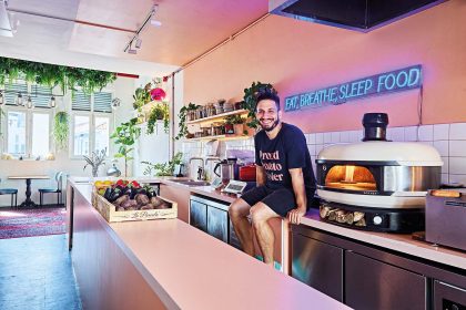 Chef Alberto Simillides designed the kitchen of Proud Potato Peeler in the style of Mediterranean homes. Next to him is a high heat pizza oven imported from Britain.