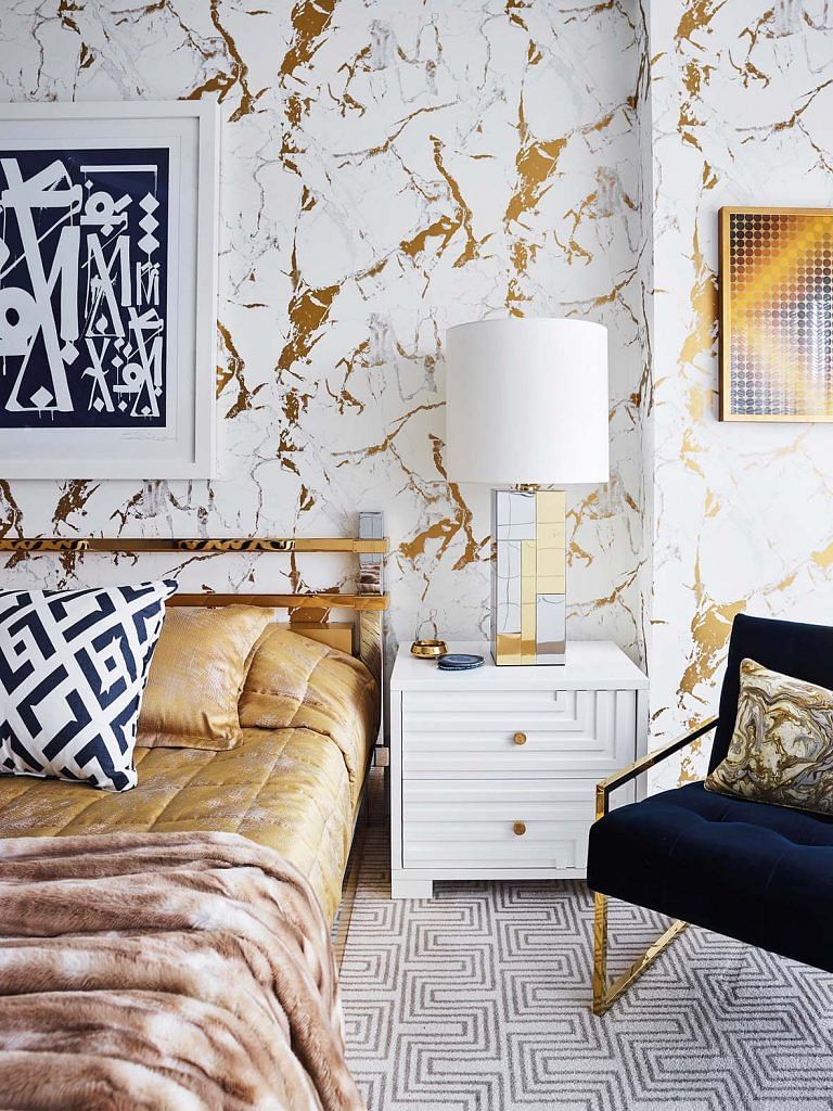 The white and gold wallpaper looks stunning against the geometric lines on the rug and side table.