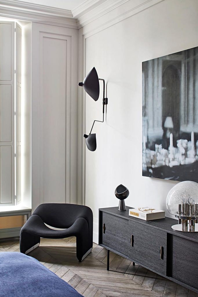 A wall sconce by Serge Mouille is a piece of art in itself. A Pierre Paulin chair and art by Paul Stanley complete the ensemble in one corner of the bedroom.
