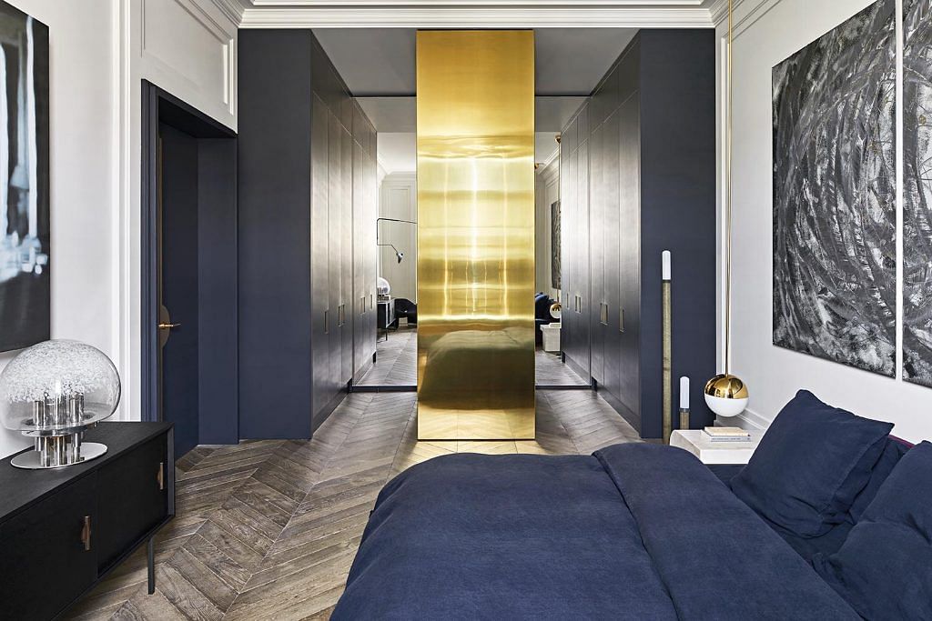 A brass door anchors the bedroom space with its height and finish.