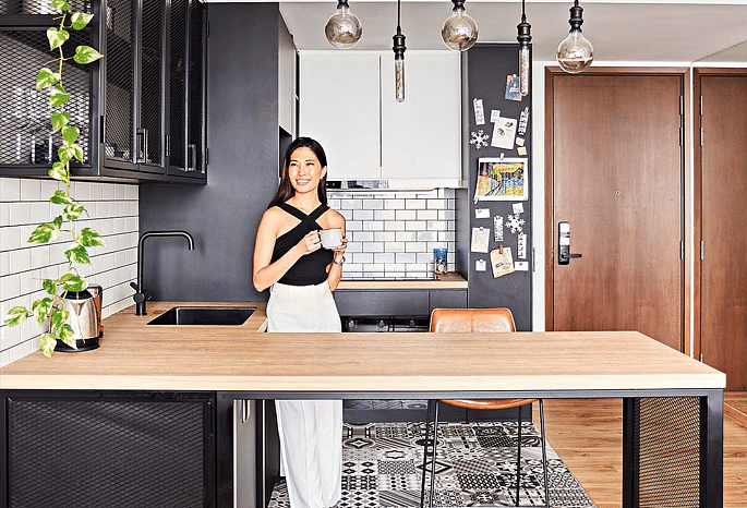 Homeowner Ingrid Liew enjoying a cuppa in her chic industrial-style open kitchen.