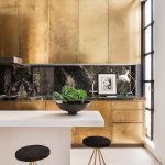 Brushed gold Bulthaup cabinetry in the kitchen area, and the black marble backsplash, makes the space feel more intimate.