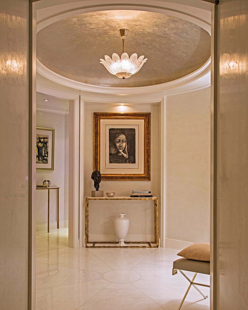 The elliptical entrance hall has a domed ceiling with an antique Orrefors light fixture. Slabs of lightly polished Afyon white marble were cut and laid in a pie wedge pattern to echo the elliptical space.