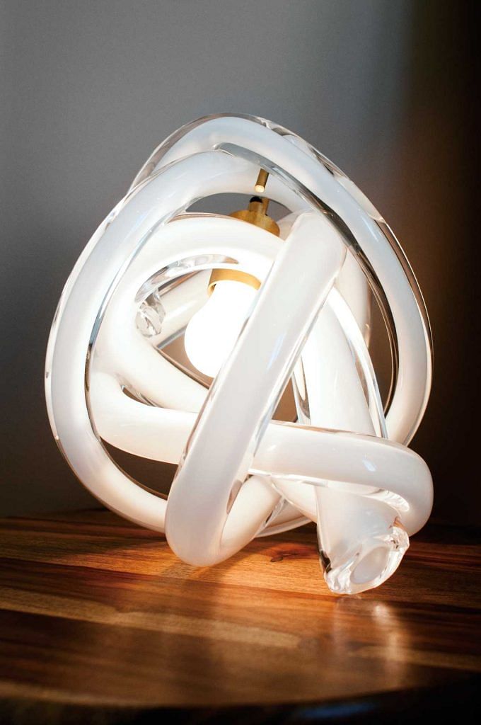 SkLO Wrap table lamp ($2,199) in white glass, brushed brass, and black cord