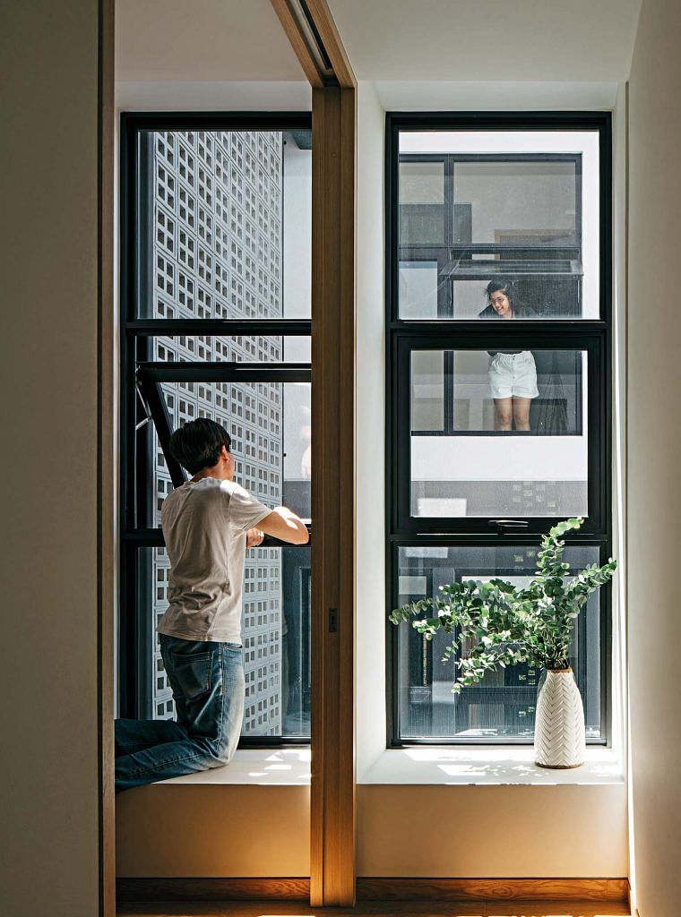 A man opening windows facing the inside of the home