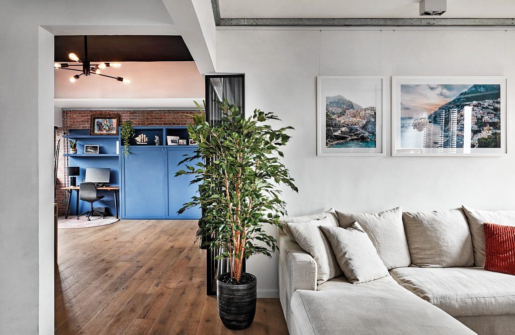 The team removed most of the walls to make this free-flowing apartment a reality. By introducing art, plants, and lighting, the design team brought visual interest and warmth to the home.
