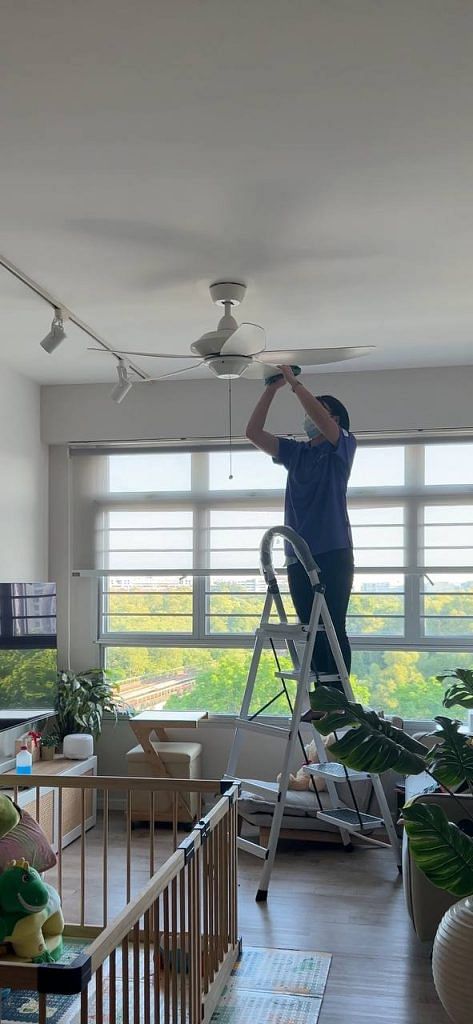 urban company helper cleaning ceiling fan in a HDB